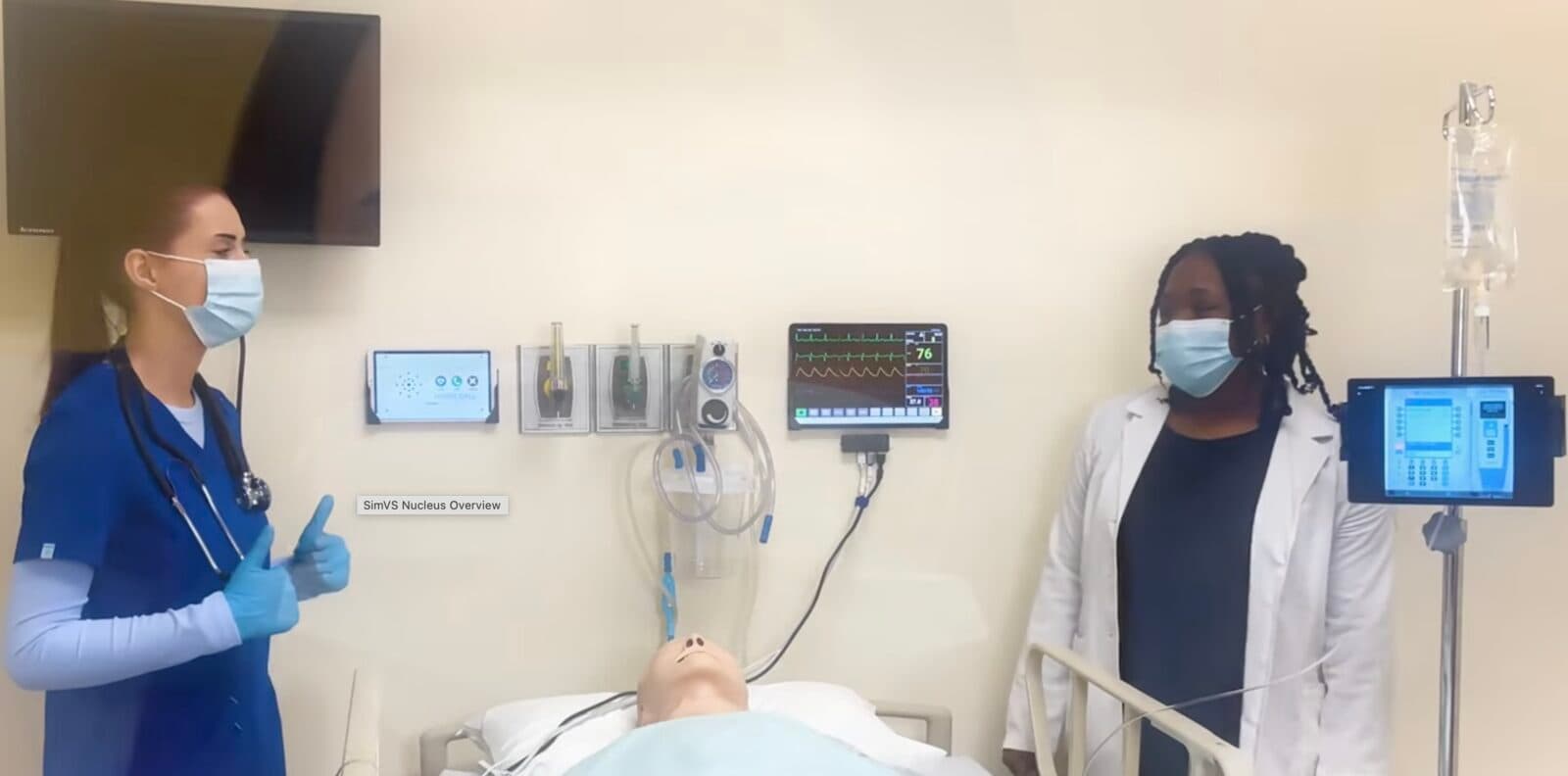 Two clinicians practicing patient care alongside SimVS simulation monitors in a hospital sim lab