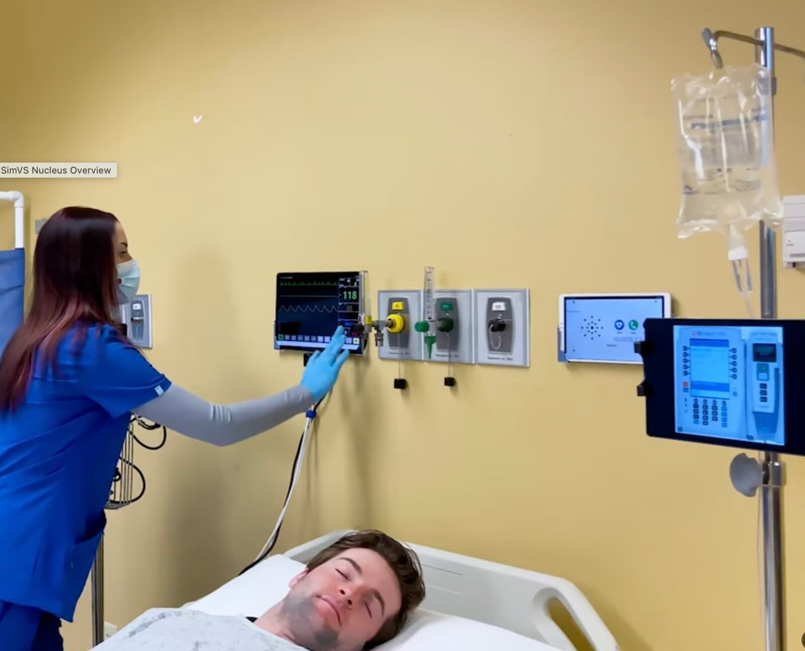 Nurse using wall-mounted SimVS patient monitor during clinical simulation training