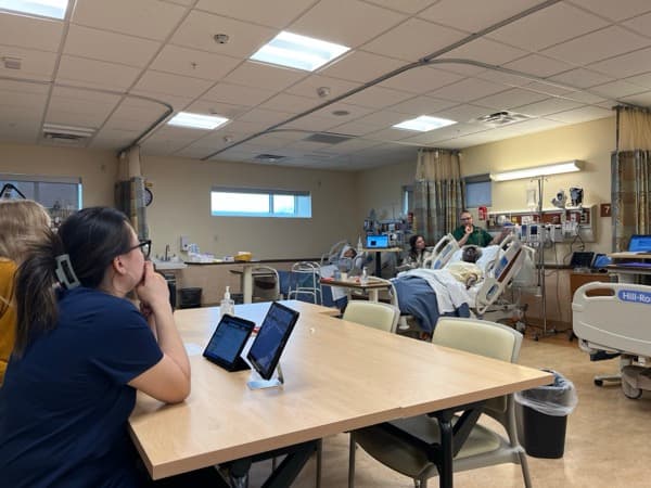 Faculty follow a live SimVS session on tablets during a multi-bed lab exercise